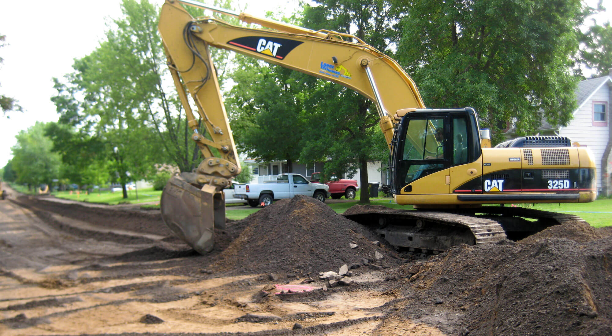 Large CAT excavator providing road maintenance in a residential area